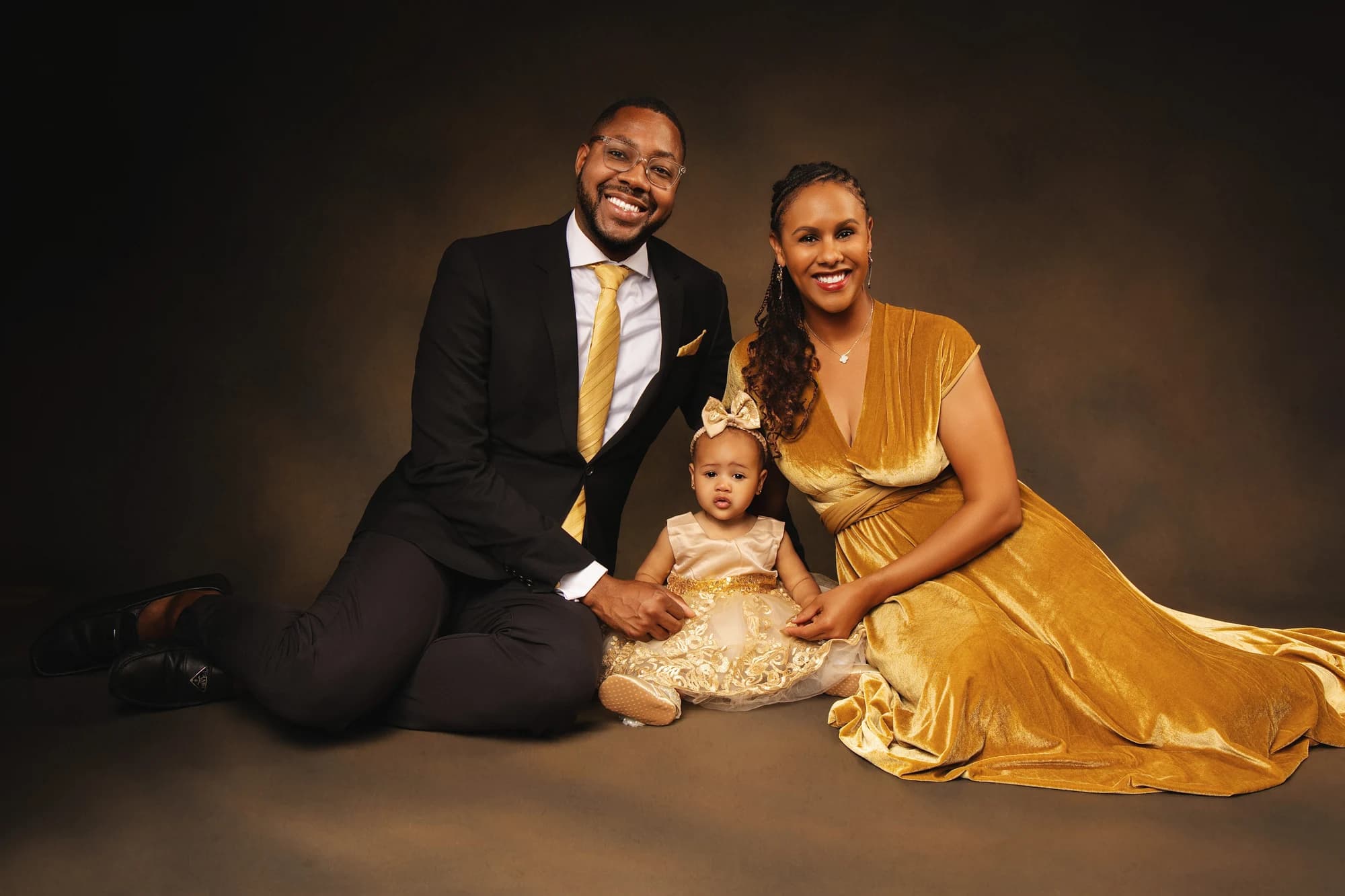 Parents and their young daughter seated together in coordinated gold and black outfits