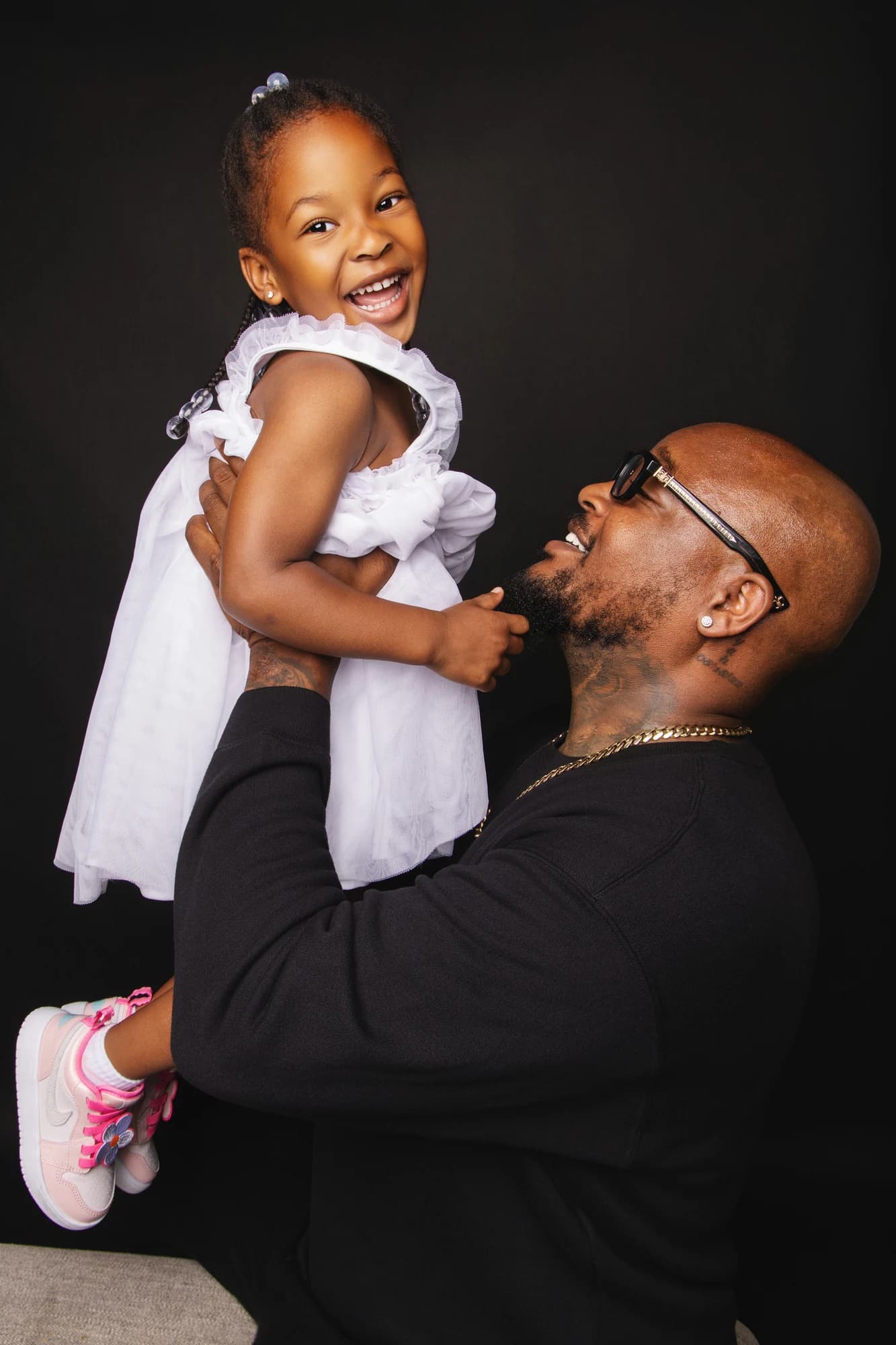 A father lifting his smiling daughter in a white dress